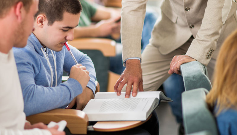 Student and teacher looking at textbook