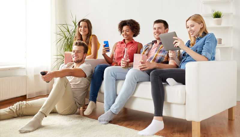 Friends watching TV, playing on phone and tablet