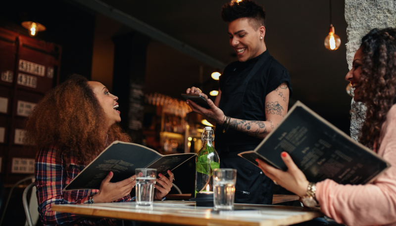 Diners holding menus talking to server